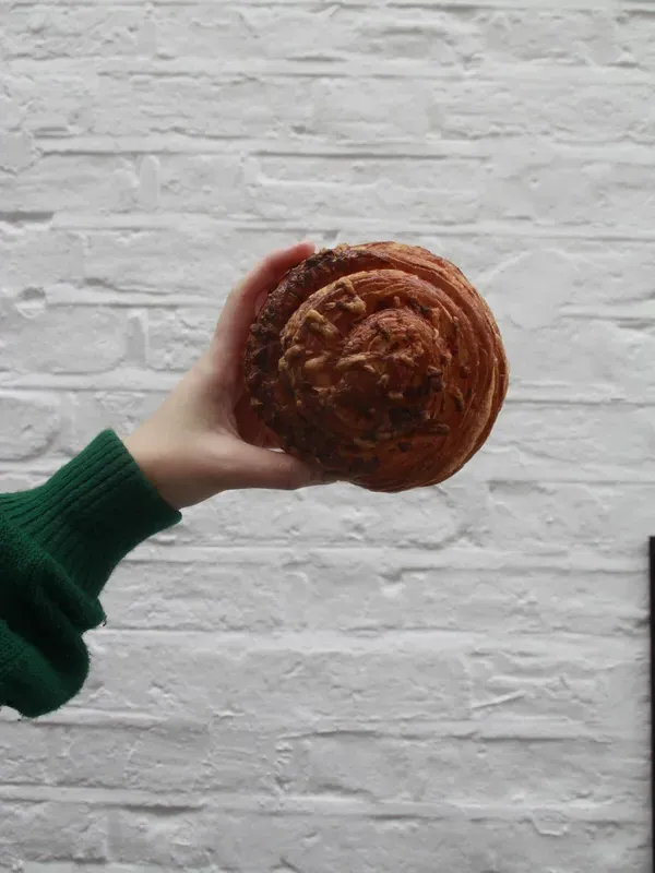 Fresh pastry held up against a white textured wall at Carbon Kopi